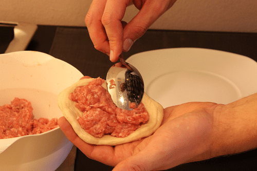 Die Fleischmasse in den Brötchenteig füllen Die Fleischmasse in den Brötchenteig füllen